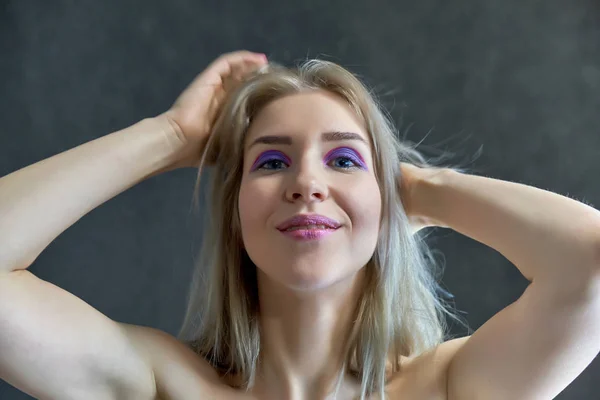 Concepto de retrato de cerca de una hermosa chica rubia sobre un fondo gris. El cabello se desarrolla en diferentes direcciones . — Foto de Stock