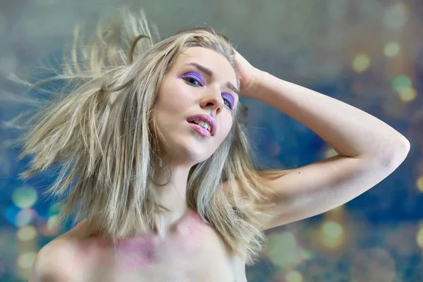 Nahaufnahme Portraitkonzept eines schönen blonden Mädchens auf einem mehrfarbigen Hintergrund. Haare entwickeln sich in verschiedene Richtungen. — Stockfoto