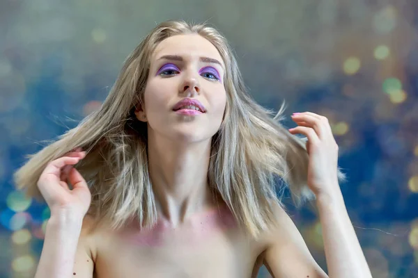 Close-up portrait concept of a beautiful blonde girl on a multi-colored background. Hair develops in different directions. — Stock Photo, Image