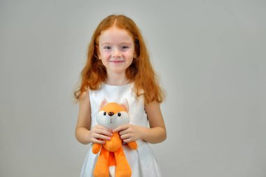 Gülümseyen ve konuşurken gri bir arka plan üzerinde kırmızı saçlı sevimli güzel çocuk kız portresi kavramı