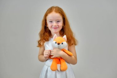 Gülümseyen ve konuşurken gri bir arka plan üzerinde kırmızı saçlı sevimli güzel çocuk kız portresi kavramı