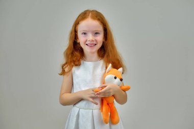 Gülümseyen ve konuşurken gri bir arka plan üzerinde kırmızı saçlı sevimli güzel çocuk kız portresi kavramı