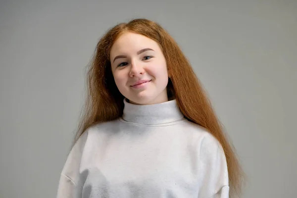 Концепт портрет милої красивої дівчини-підлітка з рудим волоссям на сірому фоні посміхаючись і розмовляючи . — стокове фото