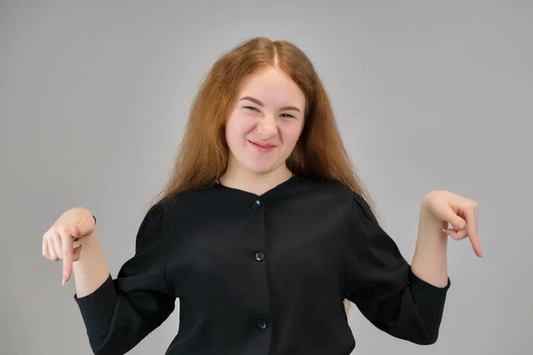 Concepto retrato de una linda adolescente con el pelo rojo sobre un fondo gris sonriendo y hablando . —  Fotos de Stock