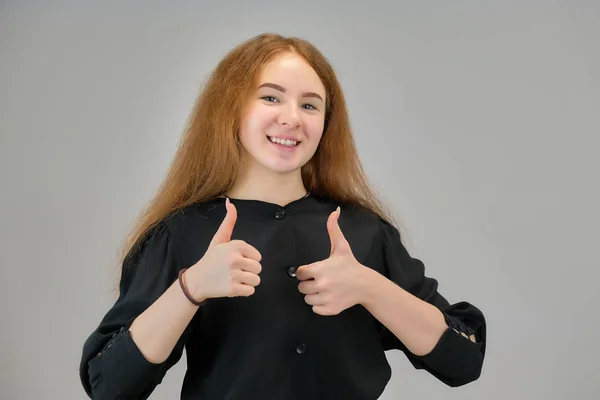 Concept retrato de uma linda menina adolescente com cabelo vermelho em um fundo cinza sorrindo e falando . — Fotografia de Stock