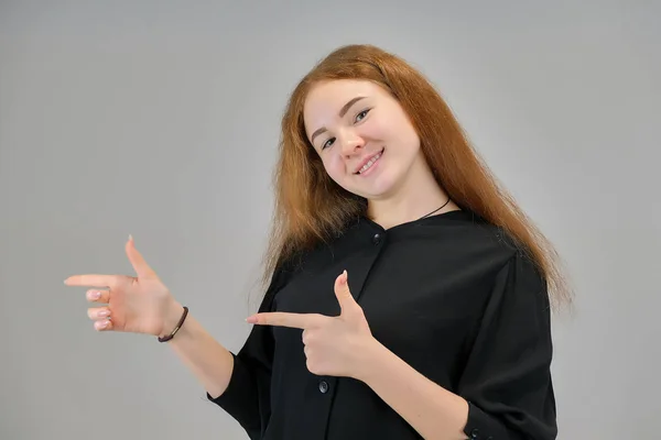 Concept retrato de uma linda menina adolescente com cabelo vermelho em um fundo cinza sorrindo e falando . — Fotografia de Stock