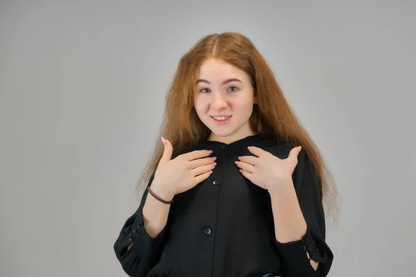 Concepto retrato de una linda adolescente con el pelo rojo sobre un fondo gris sonriendo y hablando . —  Fotos de Stock