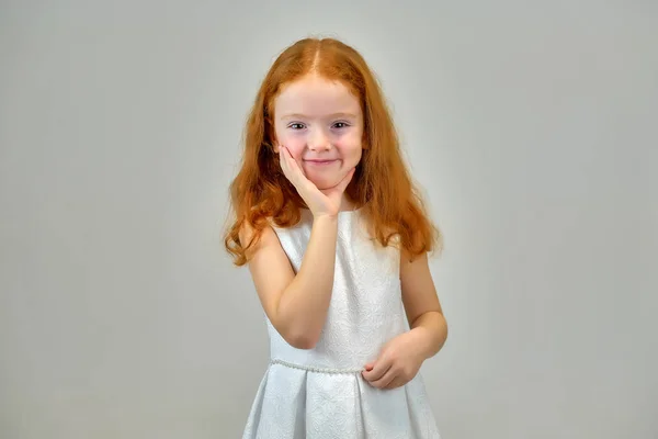 Retrato conceptual de una linda niña bonita con el pelo rojo sobre un fondo gris sonriendo y hablando —  Fotos de Stock