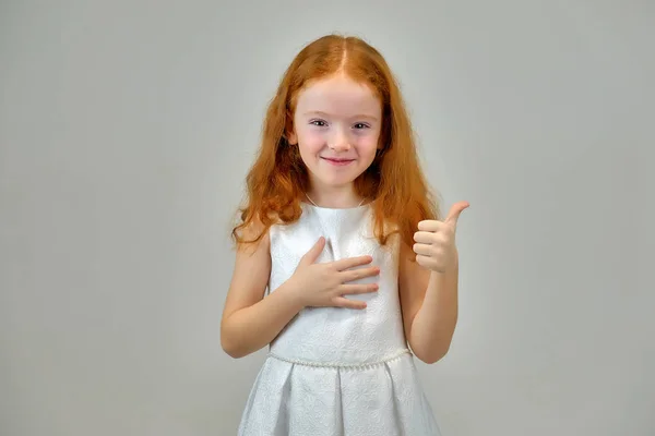 Retrato conceptual de una linda niña bonita con el pelo rojo sobre un fondo gris sonriendo y hablando —  Fotos de Stock