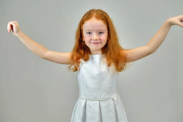 Concept retrato de uma menina bonita bonito com cabelo vermelho em um fundo cinza sorrindo e falando — Fotografia de Stock