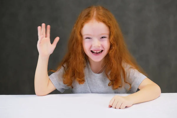 Концептуальный портрет милой красивой девочки с рыжими волосами на сером фоне, улыбающейся и говорящей . — стоковое фото