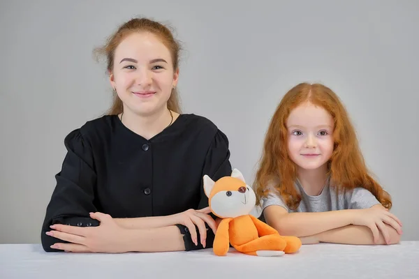 Retrato de conceito de duas irmãs bonitas bonito meninas com cabelo vermelho em um fundo cinza sorrindo e falando . — Fotografia de Stock