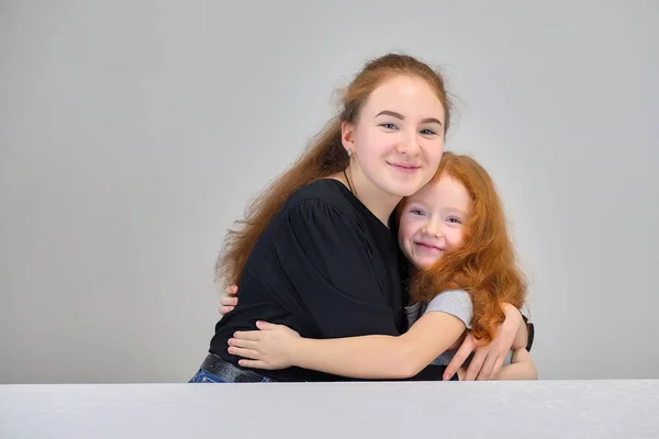 笑顔でお返事に灰色の背景に赤い髪の 2 つのかわいい可愛い女の子姉妹の概念の肖像画. — ストック写真