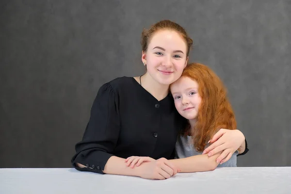 Concepto retrato de dos lindas hermanas guapas con el pelo rojo sobre un fondo gris sonriendo y hablando . —  Fotos de Stock