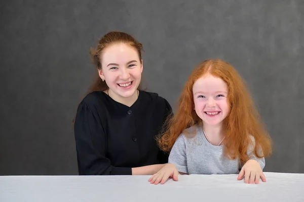 笑顔でお返事に灰色の背景に赤い髪の 2 つのかわいい可愛い女の子姉妹の概念の肖像画. — ストック写真