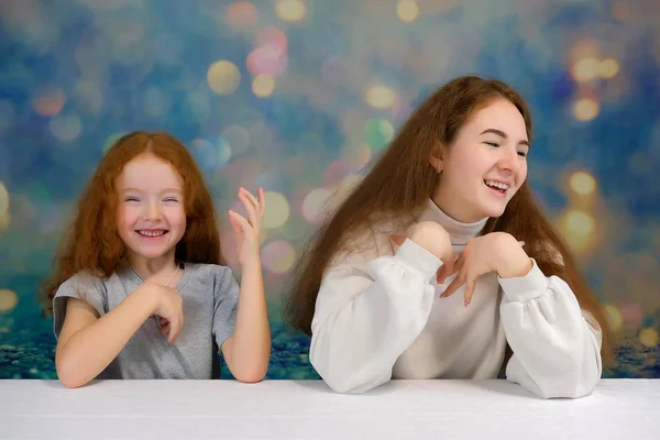 Begreppet porträtt av två söt vackra flickor systrar med rött hår på en färgbakgrund ler och talar. — Stockfoto