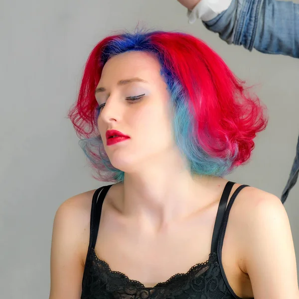 Portrait d'un coiffeur maquilleur esthéticien. Modèle aux cheveux rouges multicolores. Lavage de la tête, teinture, application de maquillage, coiffure . — Photo
