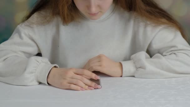 Menina adolescente bonita folheando através smarfon em um fundo colorido . — Vídeo de Stock