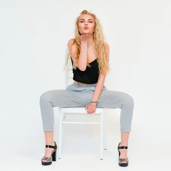 Model meisje zit op een stoel met een perfecte frisse schone huid. Foto van blonde vrouwelijk model met witte tanden kijken naar camera en glimlachen. — Stockfoto