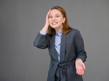 Gri arka plan üzerinde duran bir güzel genç iş kadın portresi. Doğal makyaj ve güzel bir gülümseme ile mutlu gülen genç kız.