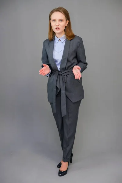 Ritratto di una bella giovane donna d'affari in piedi su sfondo grigio. Una giovane ragazza felice che ride con un trucco naturale e un bel sorriso . — Foto Stock