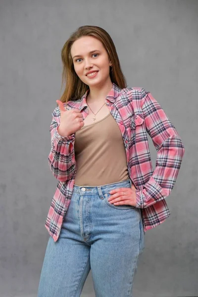 Retrato de soncept jovem alegre morena de cabelos compridos em roupas casuais em jeans azul apertado e uma camisa xadrez . — Fotografia de Stock