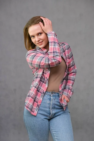 Portrét soncept mladé veselá dlouhé vlasy brunetka žena v neformálním oblečení v těsné džíny a kostkované košili. — Stock fotografie