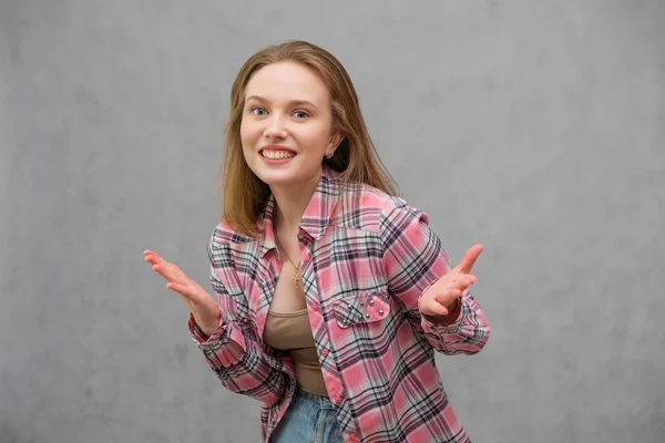 Portrait of soncept young cheerful long-haired brunette woman in casual clothes in tight blue jeans and a checkered shirt. — Stock Photo, Image
