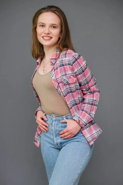 Retrato de soncept jovem alegre morena de cabelos compridos em roupas casuais em jeans azul apertado e uma camisa xadrez . — Fotografia de Stock