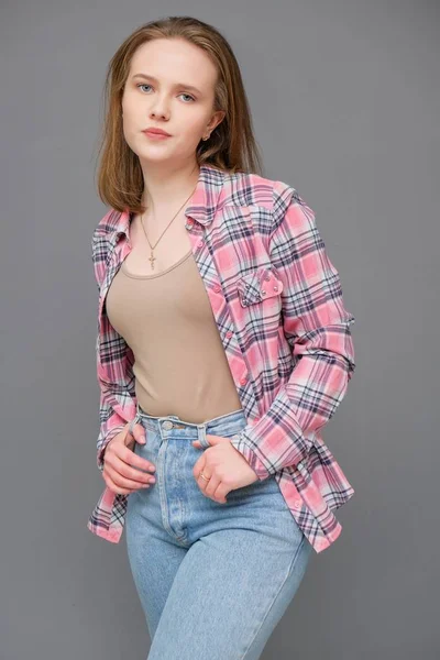 Portrait de soncept jeune femme brune aux cheveux longs joyeuse en vêtements décontractés en jeans bleu serré et une chemise à carreaux . — Photo