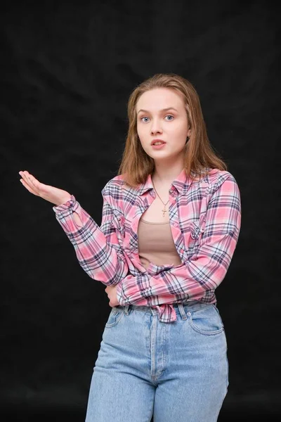 Portrait of soncept young cheerful long-haired brunette woman in casual clothes in tight blue jeans and a checkered shirt. — Stock Photo, Image