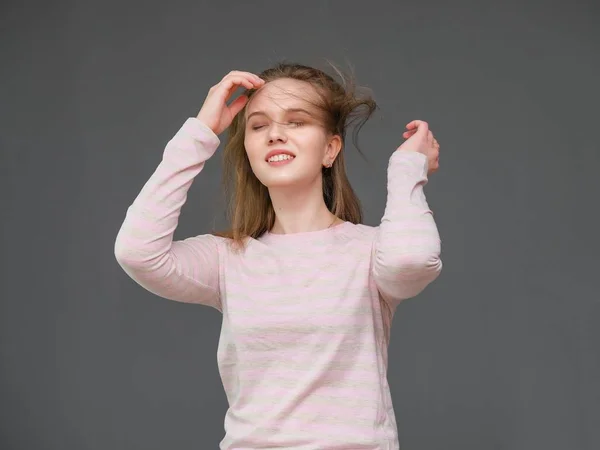 Porträt einer jungen, fröhlichen, langhaarigen, brünetten Frau, die lässig gekleidet steht, die Haare schüttelt und spricht. — Stockfoto