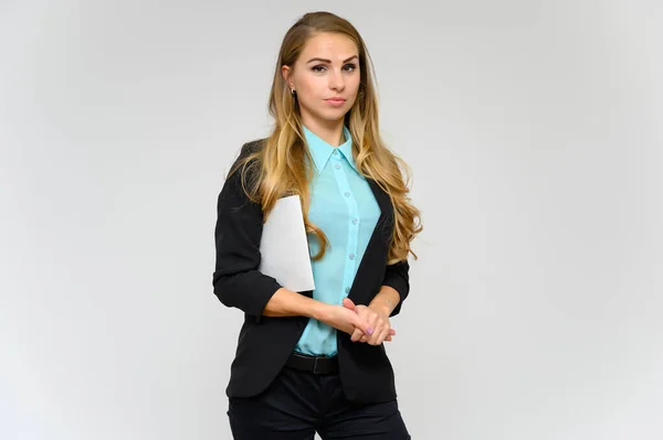 Retrato de una hermosa secretaria financiera rubia con el pelo rizado largo en un traje de negocios de pie en el estudio sobre un fondo blanco con emociones en diferentes poses con una carpeta en las manos . — Foto de Stock