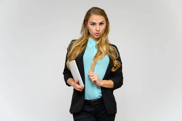 Retrato de una hermosa secretaria financiera rubia con el pelo rizado largo en un traje de negocios de pie en el estudio sobre un fondo blanco con emociones en diferentes poses con una carpeta en las manos . — Foto de Stock