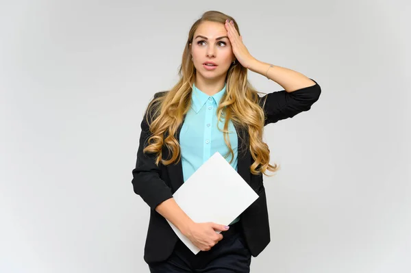 Ritratto di una graziosa segretaria finanziaria bionda con lunghi capelli ricci in un abito da lavoro in piedi in studio su uno sfondo bianco con emozioni in pose diverse con una cartella in mano . — Foto Stock