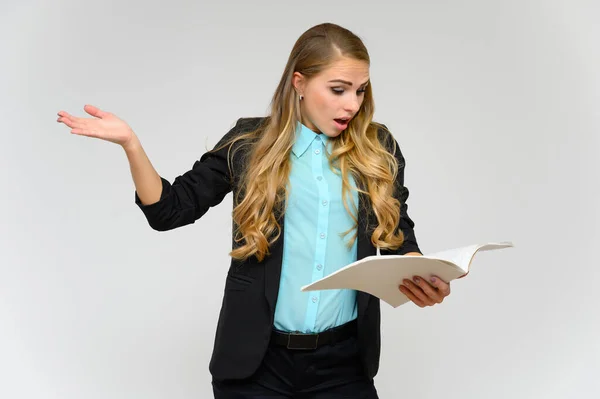 Ritratto di una graziosa segretaria finanziaria bionda con lunghi capelli ricci in un abito da lavoro in piedi in studio su uno sfondo bianco con emozioni in pose diverse con una cartella in mano . — Foto Stock