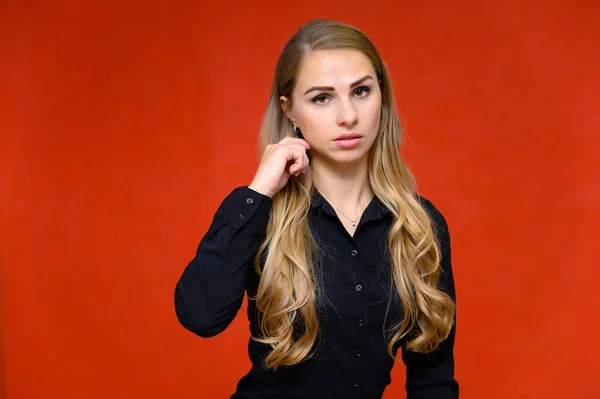 Портрет красивой блондинки финансового секретаря девушки с длинными вьющимися волосами в деловом костюме, стоящей в студии на красном фоне с эмоциями в разных позах . — стоковое фото