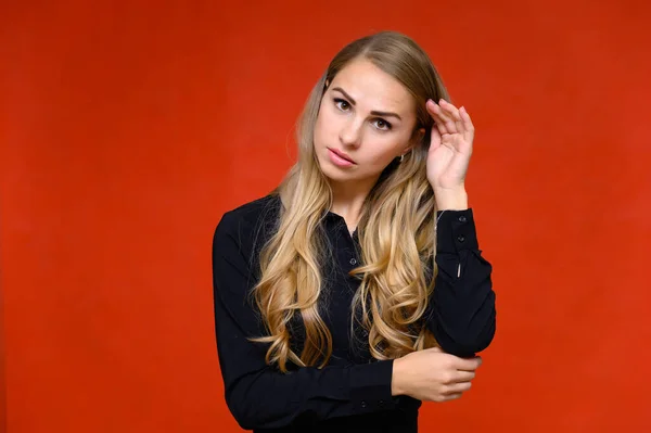 Portret van een mooi blond financieel secretaresse meisje met lang krullend haar in een zakenpak in de studio op een rode achtergrond met emoties in verschillende poses. — Stockfoto
