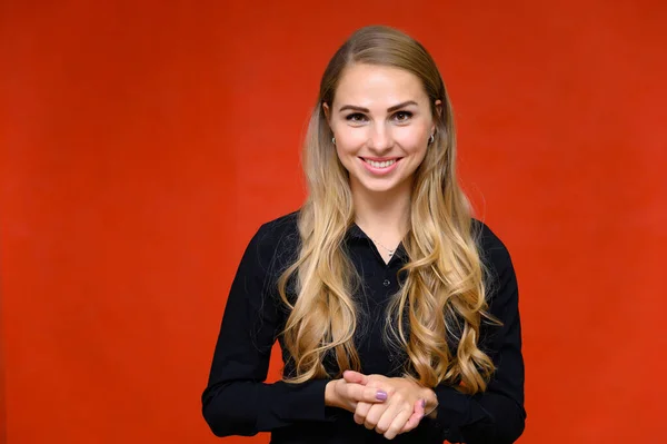 Portrait of a pretty blonde financial secretary girl with long curly hair in a business suit standing in the studio on a red background with emotions in different poses. — Stock Photo, Image