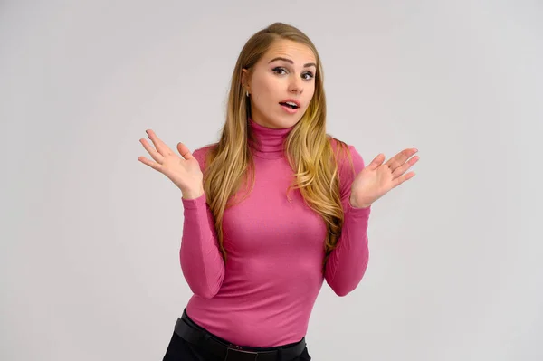 긴 곱슬머리의 금발 소녀의 근육질 초상화 가 스튜디오 배경에 흰색 배경에 다른 포즈로 핑크 색 스웨터를 입고 있다. 미, 모델, 화장품 — 스톡 사진