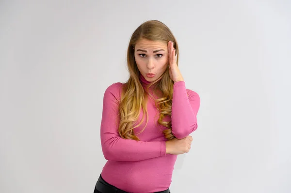 Retrato close-up de uma linda garota loira com cabelos longos encaracolados em pé no estúdio em um fundo branco com emoções em diferentes poses em uma camisola rosa. Beleza, Modelo, Cosméticos — Fotografia de Stock