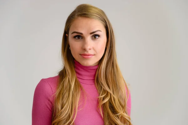 Close-up portrait of a pretty blonde girl with long curly hair standing in the studio on a white background with emotions in different poses in a pink sweater. Beauty, Model, Cosmetics — Stock Photo, Image