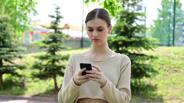 Retrato de una linda chica caucásica escribiendo emocionalmente en un teléfono inteligente — Vídeos de Stock