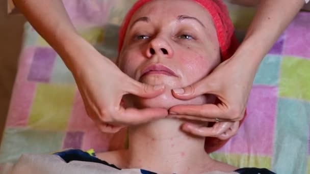 Ein Kosmetiker führt eine Gesichtsmassage durch, bei der eine Frau kurzsichtig massiert wird — Stockvideo