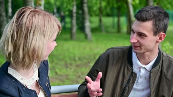 Un jeune couple parle assis sur un banc dans le parc. Le concept de conflit familial. Problèmes relationnels — Video