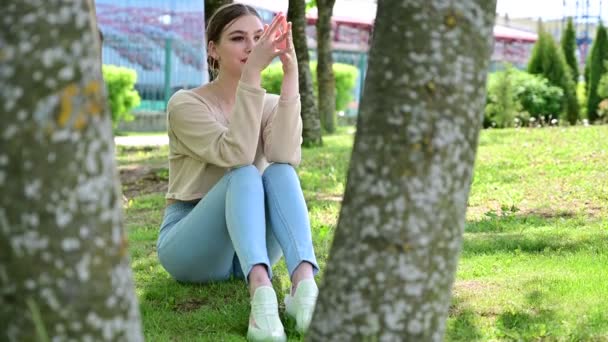 Mükemmel makyajlı Vogue Kafkas kızı güneşin altındaki bir şehir parkında oturuyor. Modaya uygun bir kadının fotoğrafı. — Stok video