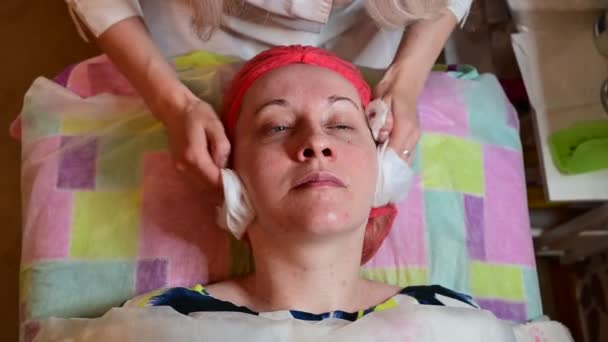 Beautician massages and cleanses the face of a woman patient. — Αρχείο Βίντεο