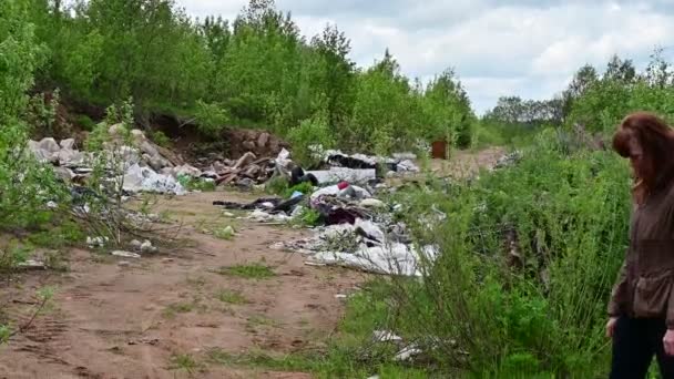 Kobieta w tle wysypiska śmieci. Człowiek chodzi i patrzy na śmieci. — Wideo stockowe