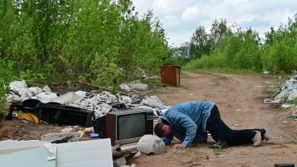 一个男人的录像躺在垃圾堆上。3.这个模型在多云的天气里慢慢地升起来,站起来,四周张望. — 图库视频影像