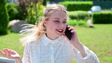 Güzel bir kadın, güneşli bir havada parkta gülümseyerek poz veriyor..